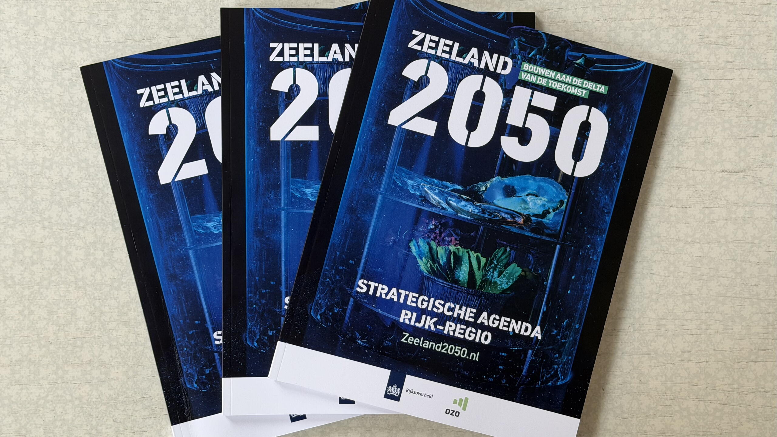 Drie exemplaren van de Strategische Agenda Zeeland 2050 Rijk-Regio op een tafel.