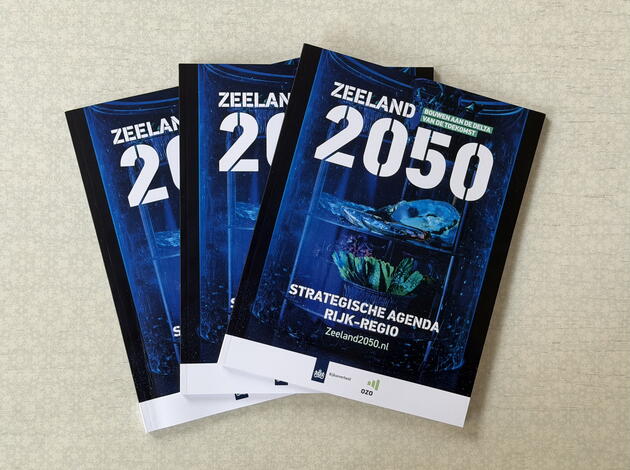Drie exemplaren van de Strategische Agenda Zeeland 2050 Rijk-Regio op een tafel.