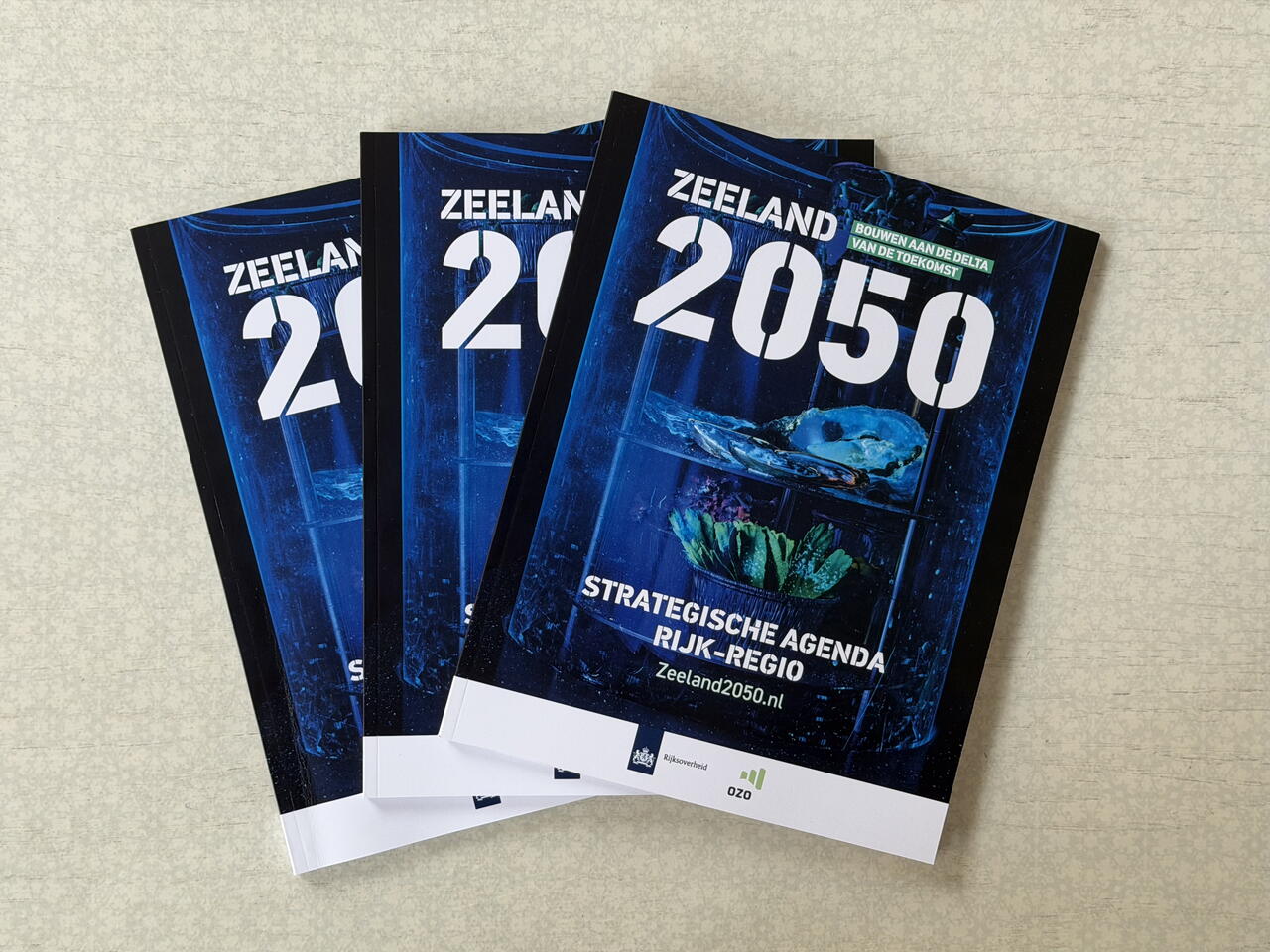 Drie exemplaren van de Strategische Agenda Zeeland 2050 Rijk-Regio op een tafel.